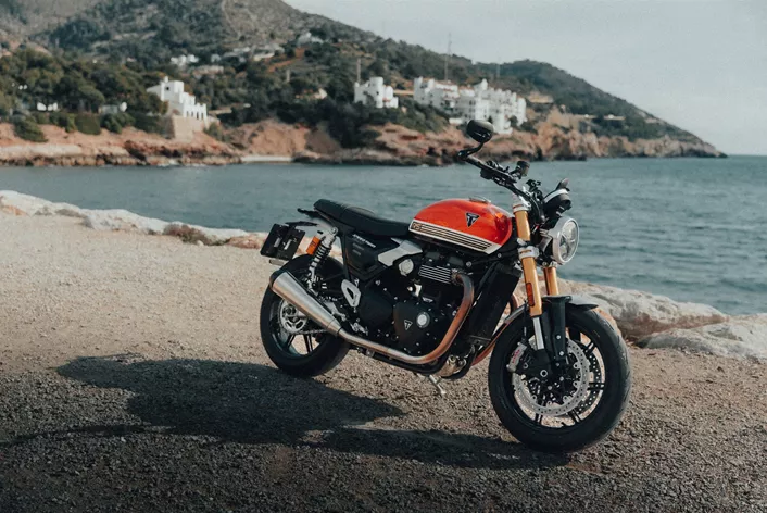 Barcelona, viel Sonnenschein, kurvige Bergstraßen – eine perfekte Kulisse für ein Motorrad, das den Spagat zwischen klassischer Eleganz und sportlicher Fahrdynamik wagt. Ich habe die Triumph Speed Twin 1200 RS mit dabei, um zu sehen, ob sie mehr ist als nur ein schicker Roadster für den Café-Besuch. Wie schlägt sie sich im längeren Gebrauch?