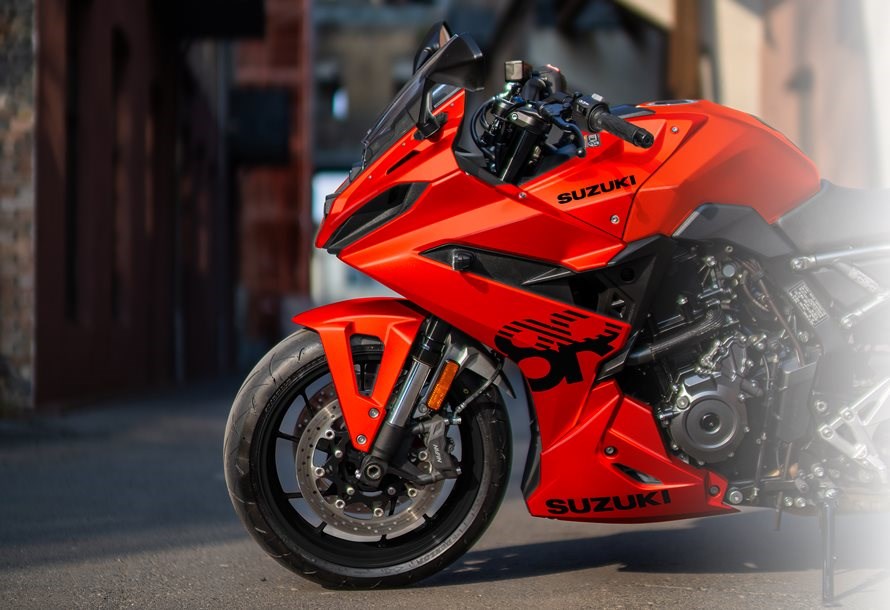 Nahaufnahme der Frontpartie und des Vorderrads einer leuchtend orangefarbenen Suzuki GSX-8R Daidai-Iro Edition vor einem urbanen Hintergrund.