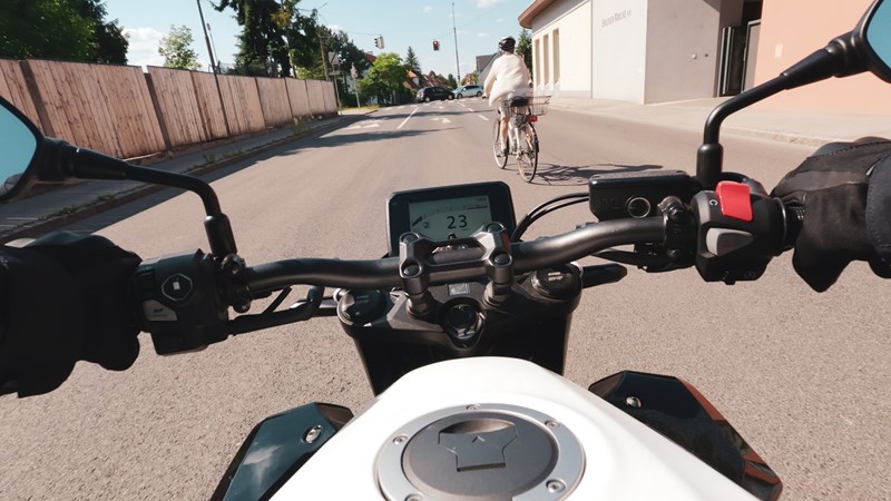 Motorradfahren lernen - eine Honda CRF1100L Africa Twin Adventure Sports DCT hinter einer Radfahrerin in der Stadt Motorradfahren lernen - eine Honda CRF1100L Africa Twin Adventure Sports DCT hinter einer Radfahrerin in der Stadt