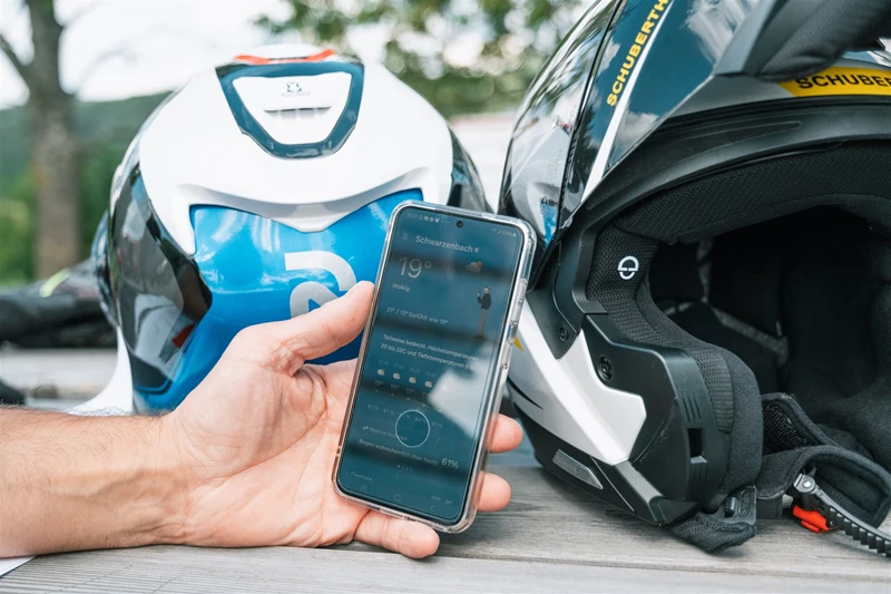 Motorradfahren lernen - ein Handy mit einer Wetterapp vor einem HJC- und einem Schuberthhelm Motorradfahren lernen - ein Handy mit einer Wetterapp vor einem HJC- und einem Schuberthhelm