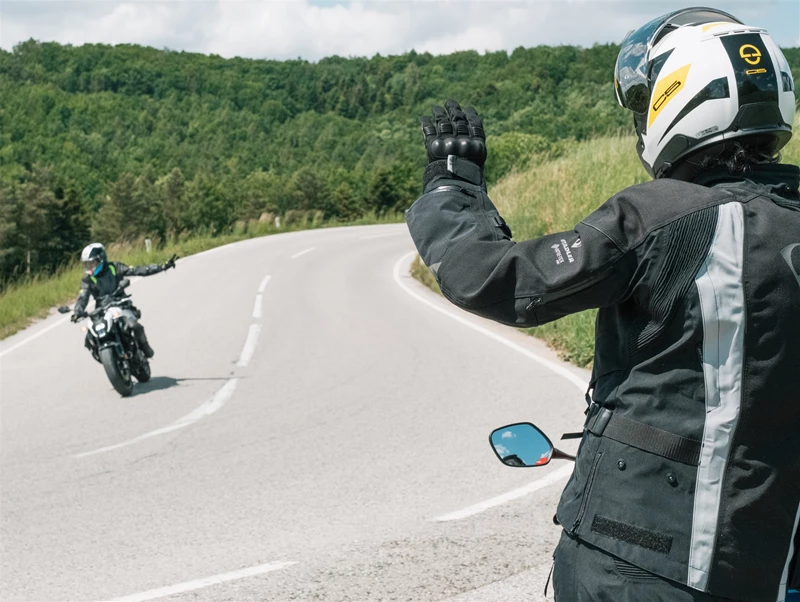 Motorradfahren lernen - ein Fahrer auf einer Honda CB500 Hornet auf der Landstraße, einen anderen Motorradfahrer grüßend Motorradfahren lernen - ein Fahrer auf einer Honda CB500 Hornet auf der Landstraße, einen anderen Motorradfahrer grüßend