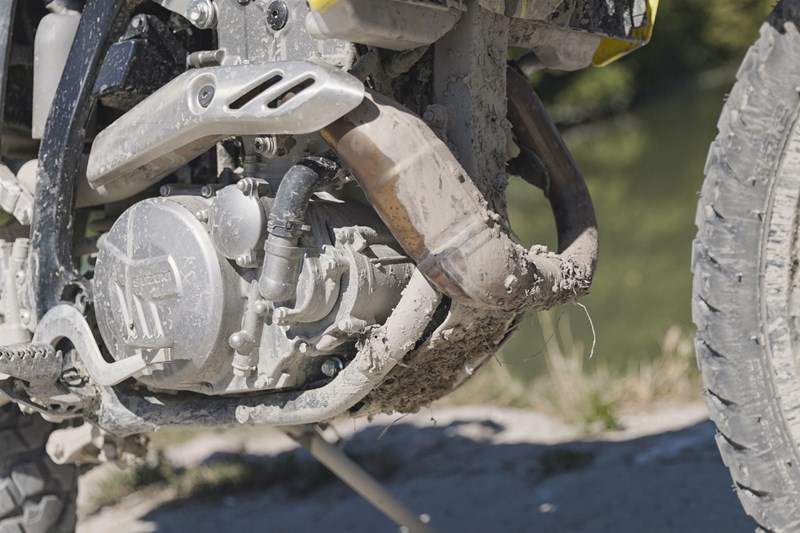Nur zwischen den zwei unteren Streben des Stahlrahmens besitzt die Suzuki eine kleine Schutzplatte für den Motor. Große Teile des Krümmers, des Motors, sowie die Handhebeleien sind in Serie ungeschützt.