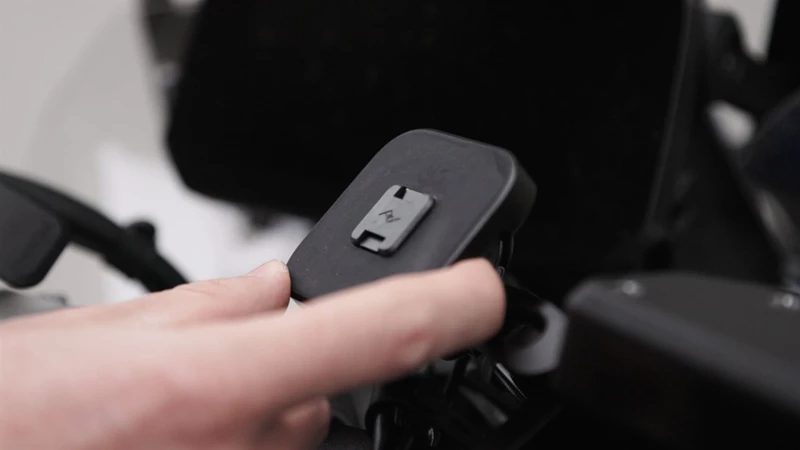 Drückt man einen der zwei seitlichen Knöpfe, ziehen sich die kleinen Sicherungshaken zurück und geben das Smartphone frei. Drückt man einen der zwei seitlichen Knöpfe, ziehen sich die kleinen Sicherungshaken zurück und geben das Smartphone frei.