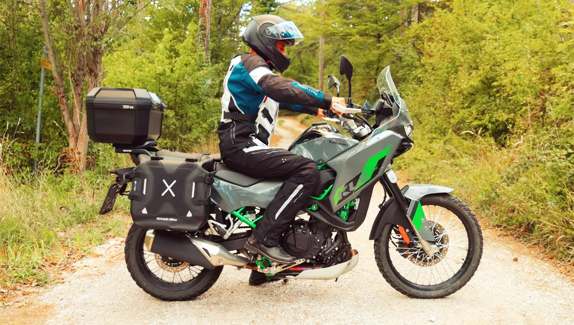 Kawasaki KLE 500 with rider standing on the gravel track